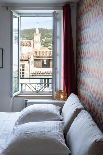 une chambre avec un lit et une grande fenêtre dans l'établissement Calme et confort en coeur de ville, à Draguignan