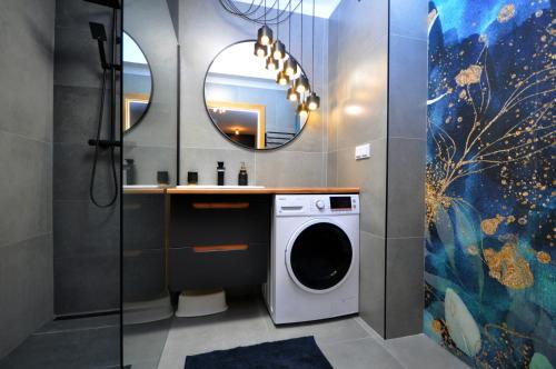 a bathroom with a washing machine and a mirror at Aquapark with private garage by JoApart in Kraków
