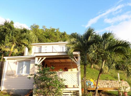 a white house with palm trees in front of it at Caraïbes Cottages Le Jasmin vue mer a 500m de la plage in Deshaies