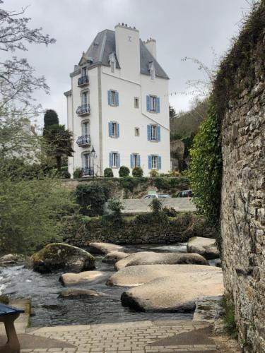 un grand bâtiment blanc au sommet d'une rivière dans l'établissement Maison Castel Braz, à Pont-Aven