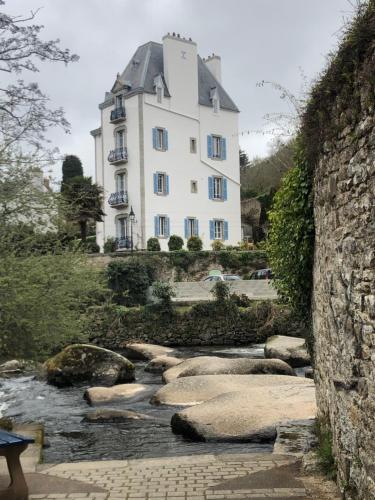 a large white building sitting on top of a river at Maison Castel Braz in Pont-Aven