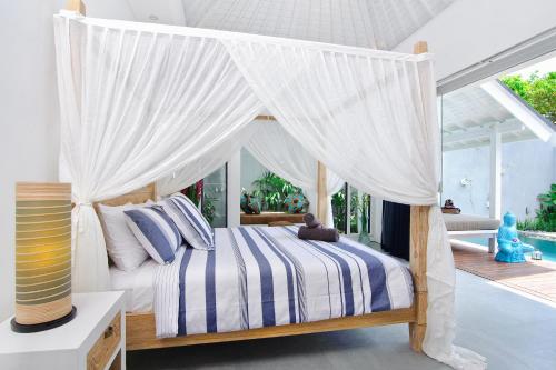 - une chambre avec un lit à baldaquin et des rideaux blancs dans l'établissement Villa Dheva, à Seminyak