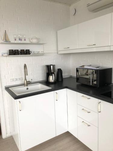 a white kitchen with a sink and a microwave at Hel(t) udlejningsbolig med Christina som vært in Gråsten