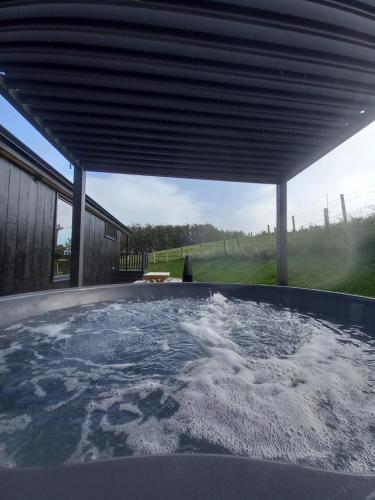 a hot tub under a cover in a backyard at Briarfield Farm Stays - A Unique Coastal Getaway in Glenarm
