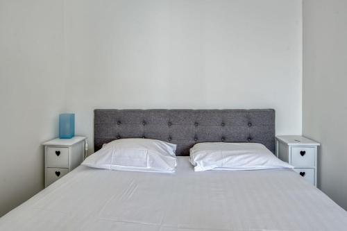 - un lit blanc avec 2 tables de chevet et un vase bleu dans l'établissement Appartement Rivage - Welkeys, à Cagnes-sur-Mer