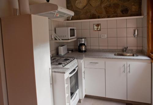 uma cozinha com armários brancos e um forno de fogão branco em Lodge Rio Andino em Ushuaia