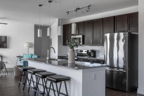 a kitchen with a stainless steel refrigerator and some bar stools at Mint House Nashville - Music Row in Nashville