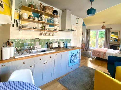 uma cozinha com armários brancos e um lavatório num quarto em St Ives Balcony Flat em St Ives