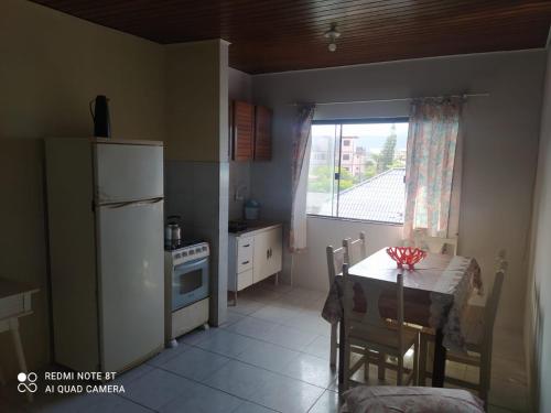 una pequeña cocina con mesa y nevera en Residencial Avila Frente Ao Mar en Florianópolis