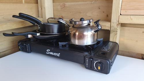 a tea kettle and pans on top of a stove at Calon Y Goedwig Glamping in Llandovery