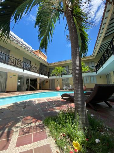 a palm tree in front of a building with a swimming pool at Najhomi Beach in Santa Marta