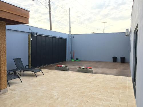 a patio with two chairs and flowers and a fence at Cantinho Estrelado - Casa automatizada com ALEXA in Brotas
