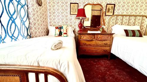 a bedroom with two beds and a dresser and a mirror at Hotel La More at The Bisbee Inn in Bisbee