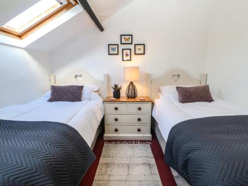 two twin beds in a room with a night stand at Englewood Cottage in Allenheads