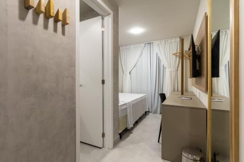 a small room with a bed and a desk and a window at Liiv Mar - Natal Ponta Negra in Natal