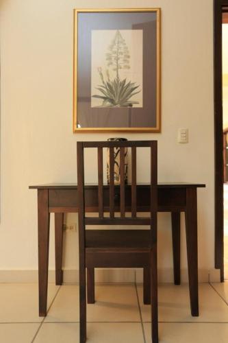 a wooden table with a chair under a picture at Hotel Plaza Yat Balam Anexo in Copan Ruinas