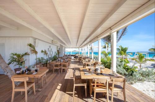 a restaurant on the beach with wooden tables and chairs at Top floor unit 520 ft2 - 48 m2 with stunning dominant view on ocean, St Barth, Orient Bay in Cul de Sac
