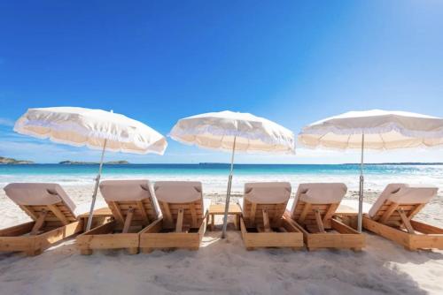 a group of chairs and umbrellas on a beach at Top floor unit 520 ft2 - 48 m2 with stunning dominant view on ocean, St Barth, Orient Bay in Cul de Sac