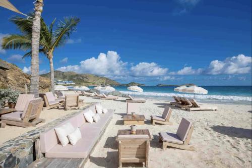 a beach with chairs and umbrellas and the ocean at Top floor unit 520 ft2 - 48 m2 with stunning dominant view on ocean, St Barth, Orient Bay in Cul de Sac