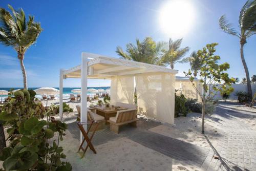 a white pavilion on the beach with palm trees at Top floor unit 520 ft2 - 48 m2 with stunning dominant view on ocean, St Barth, Orient Bay in Cul de Sac