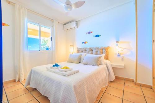a white bed in a room with a window at Primera linea de playa , increíbles vistas, amplio in La Mata