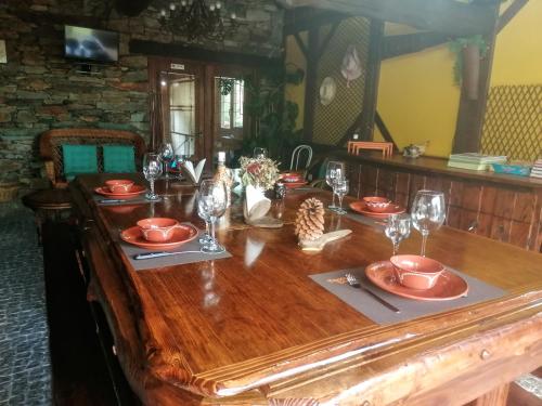 a wooden table with plates and wine glasses on it at Quinta das Courelinhas - Alojamento Local - Serra da Estrela in Unhais da Serra