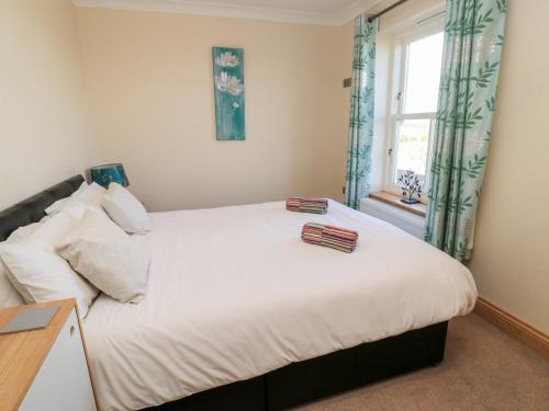 a bedroom with a large white bed and a window at Bank Top Cottage in Embleton