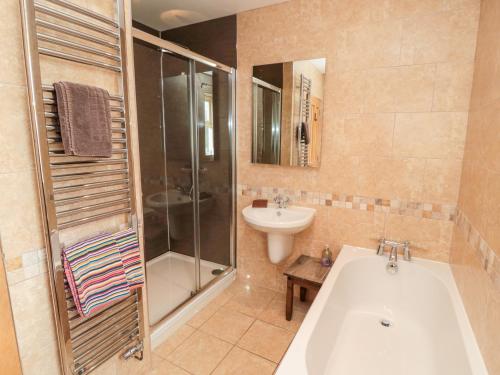 a bathroom with a tub and a sink and a shower at Bank Top Cottage in Embleton