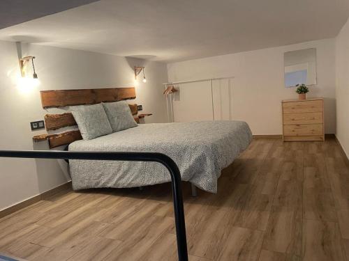 Un dormitorio con una cama y suelo de madera. en Precioso loft en Olula del Río, en Olula del Río
