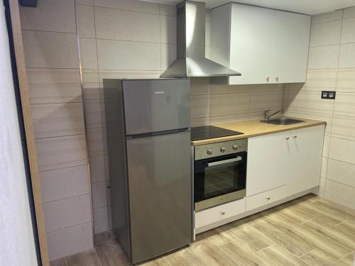Una cocina con frigorífico de acero inoxidable y fregadero. en Precioso loft en Olula del Río, en Olula del Río