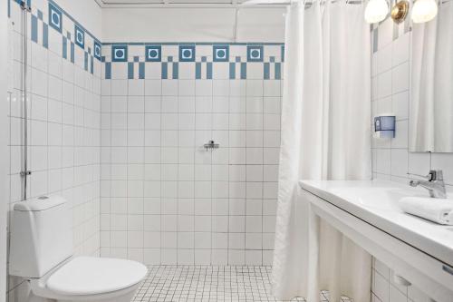 ein weißes Bad mit einem WC und einer Dusche in der Unterkunft Amals Stadshotell, Sure Hotel Collection by Best Western in Åmål