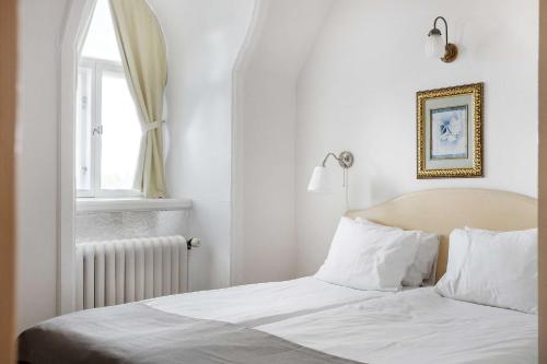 a bedroom with a bed with white sheets and a window at Amals Stadshotell, BW Signature Collection in Åmål