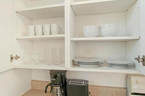 a kitchen with white cabinets with plates and dishes at Complete & Polshed 1-Bedroom Chicago Apt - Elm D2 in Skokie