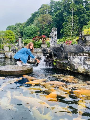 a woman is playing in a fountain in a pond at Wina Ubud B&B in Ubud
