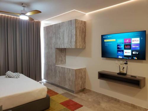 a bedroom with a bed and a flat screen tv at Estudio súper cómodo acogedor y tranquilo in Tulum