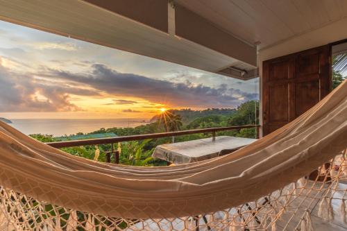 a hammock on a balcony with a sunset at Hotel Villas de la Selva in Manuel Antonio