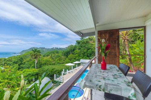 a table on a balcony with a view of the ocean at Hotel Villas de la Selva in Manuel Antonio