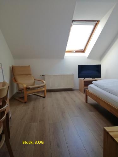 a bedroom with a bed and a chair and a television at Hotel Hanseatic-garni in Wuppertal