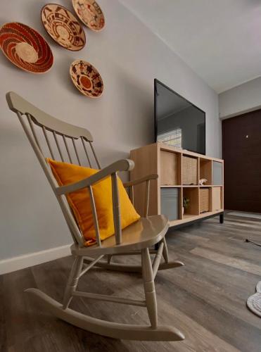a rocking chair in a living room with plates on the wall at Acogedor departamento totalmente remodelado, tranquilo y centrico in Ciudad Juárez