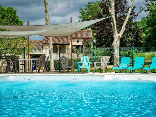 - un groupe de chaises et une piscine avec un parasol dans l'établissement Camp del Four, à Puy-lʼÉvêque