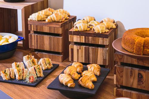 a bunch of different types of bread and pastries on plates at Novotel Lencois Paulista in Lençóis Paulista