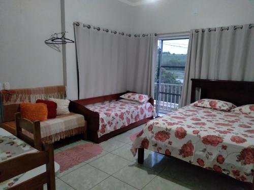 1 dormitorio con 2 camas y ventana con balcón en CANTINHO DA PAZ! en Águas de São Pedro