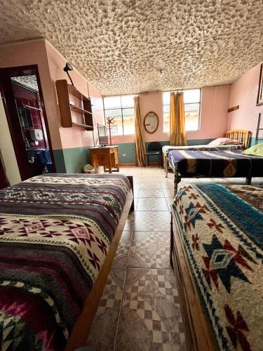 a room with two beds in a room with a ceiling at Hostal Carlos Luis in Quito