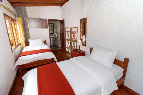 two beds in a room with white walls and wood floors at Napolitano Apart Hotel in Baños