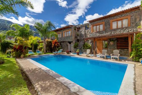 a villa with a swimming pool in front of a house at Napolitano Apart Hotel in Baños