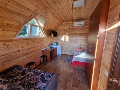 - une chambre dans une cabane en rondins avec un lit et un bureau dans l'établissement Шафран, à Krasnaya Slobodka