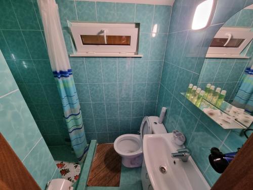 a green tiled bathroom with a toilet and a sink at Шафран in Krasnaya Slobodka