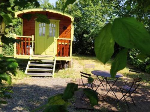 une petite cabine avec une table en face de celle-ci dans l'établissement Roulotte bucolique en bois avec terrasse, Vallée de la Sarthe - FR-1-410-188, à Chantenay-Villedieu