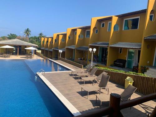 um resort com uma piscina com cadeiras e edifícios em Condomínio Imbassai Summer Flat em Imbassaí