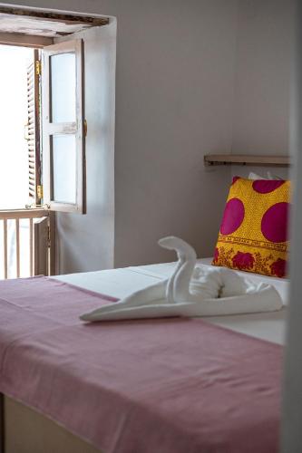 a bed with a white blanket and a window at Sharazad Wonders Boutique in Zanzibar City